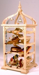 A crank is turned moving marbles to the top then they travel down two pathways