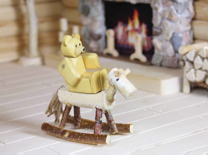 Baby bear rocks on the wood horse in front of the fireplace